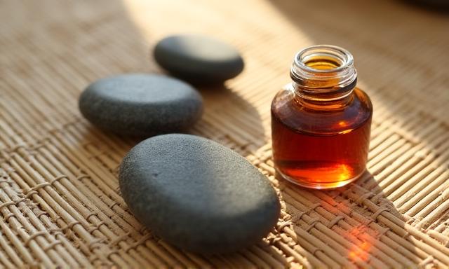 Artistic arrangement of warm basalt stones and essential oils on a bamboo mat